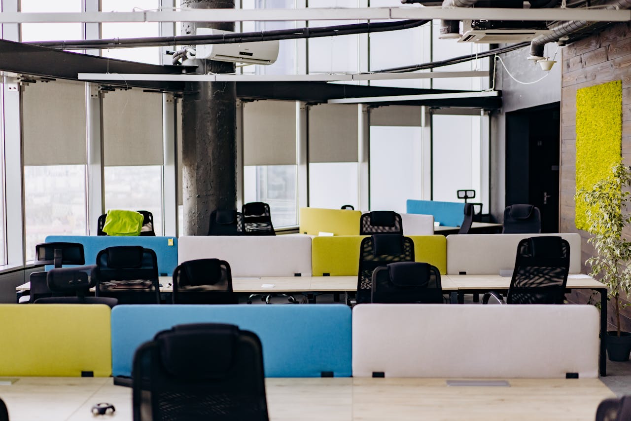 Bright and spacious open office with colorful partitioned desks and natural light.